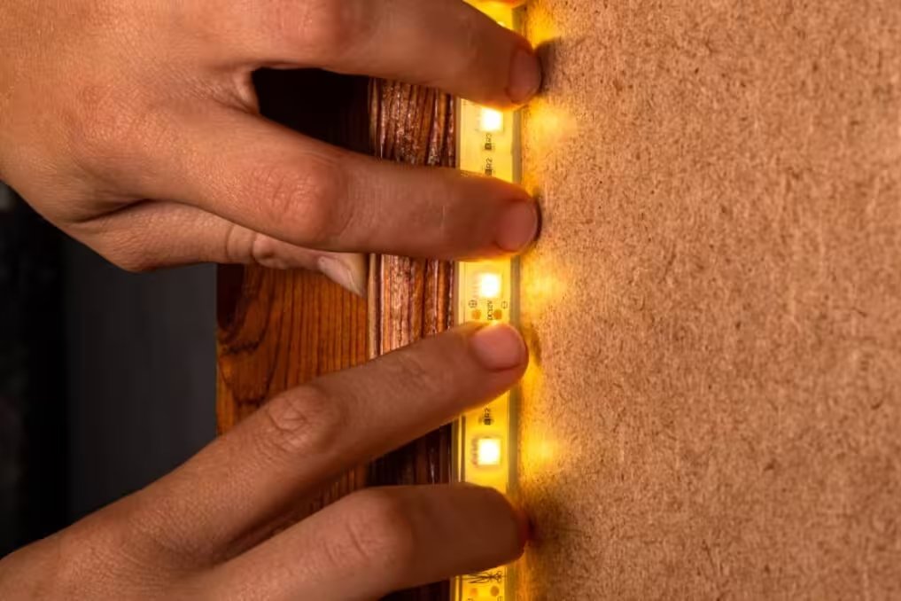 Instalador de led realizando la instalación de luces led con perfiles de aluminio bajo muebles de cocina en Medellín.